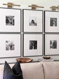 black and white photographs hang on the wall above a couch in a living room with pillows