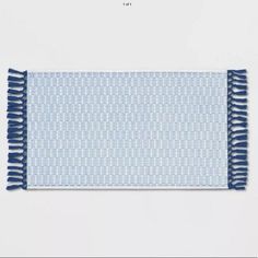 a blue and white placemat with fringes on it, in front of a white background