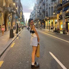 a woman standing on a skateboard in the middle of an empty city street at dusk