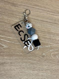 "ECSE" black and grey theme keychain with lobster claw. Made with silicon beads. Acrylic tag. Silicon Beads, Grey Theme, Silicone Beads, Lobster Claw, Key Chain, Keychains, Black And Grey, Accessory Gift, Gift Card