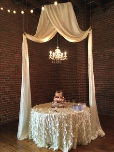 a table with a cake on it in front of a chandelier hanging from the ceiling