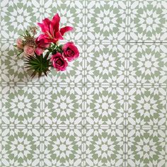 pink flowers in a vase on a green and white tiled wall