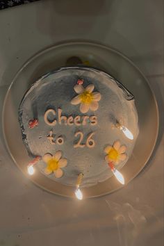 a cake with flowers and lights on it that says cheers to 26 year old in white frosting