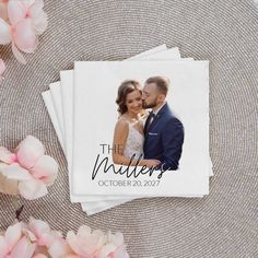 the wedding photo is on top of three napkins with pink flowers in front of it