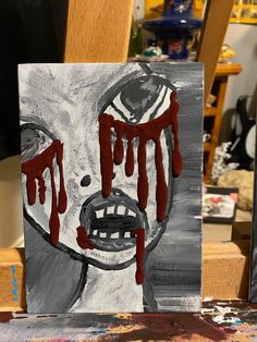 a painting with red paint dripping from it's mouth on a wooden easel