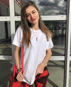 a young woman holding a red purse and posing for the camera