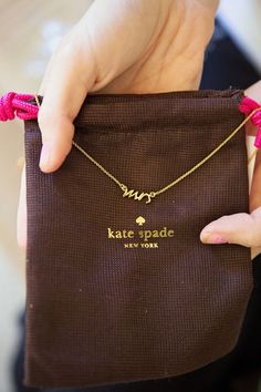 a person holding a brown bag with a name on it and the words kate cole written in gold