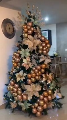 a christmas tree decorated with gold and silver ornaments in a living room next to a clock