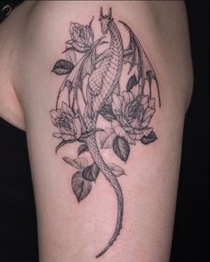 a black and white photo of a woman's arm with a dragon tattoo on it