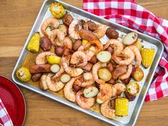 shrimp, corn and potatoes on a pan with a red checkered napkin next to it