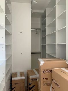 boxes are stacked on the floor in an empty room with white walls and shelving