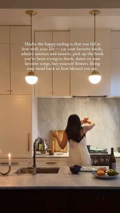 a woman standing in front of a kitchen counter with food on it and candles lit