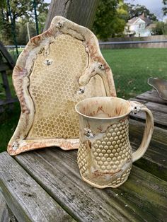 a mug and plate sitting on top of a wooden table in front of a tree