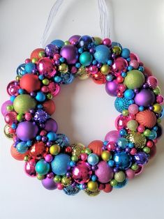 a colorful christmas ornament hanging on a white wall with ornaments in the shape of a wreath