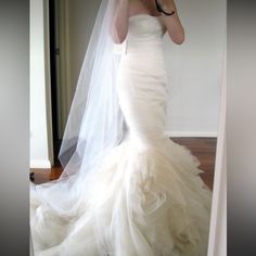 a woman in a wedding dress taking a selfie with her cell phone while wearing a veil