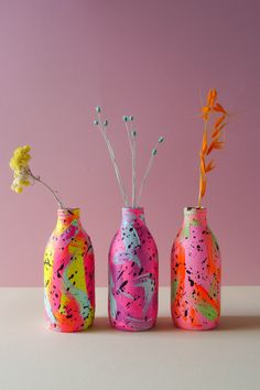 three painted vases with flowers in them