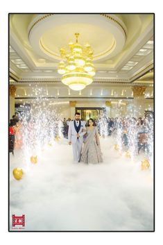 a man and woman are walking through the clouds with sparklers in front of them