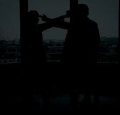 two people standing in front of a window at night