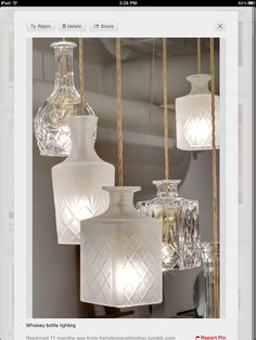 several glass vases are hanging from rope in front of a mirror and light fixture