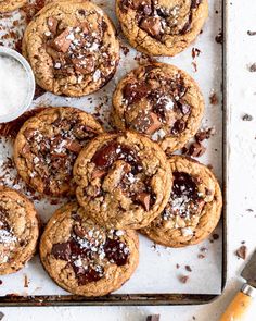 chocolate chip cookies with powdered sugar on a baking sheet next to utensils