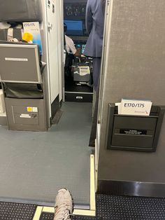 the inside of an airplane with two people standing in the doorway and one person sitting on the floor