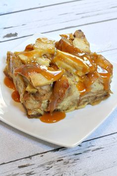 a white plate topped with french toast covered in caramel sauce and apple toppings