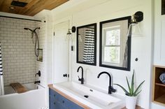 a bathroom with two sinks and a bathtub next to a window in the wall