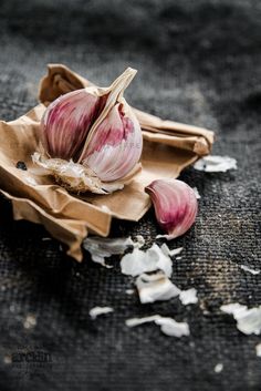 two garlics sitting on top of a piece of brown paper next to some shredded up food