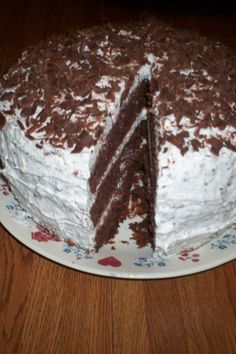 a chocolate cake with white frosting and one slice cut from it on a plate