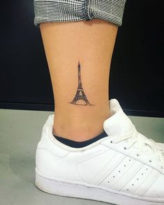 a woman's foot with a small eiffel tower tattoo on her ankle