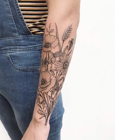 a woman's arm with flowers and leaves tattooed on the left side of her arm