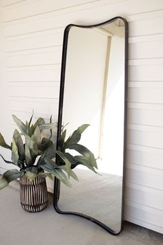 a large mirror sitting on top of a table next to a potted plant