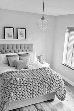 black and white photo of a bedroom with a bed, nightstands, lamps and pictures on the wall