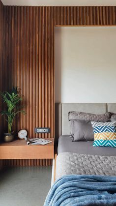 a bed sitting next to a wooden wall with pillows on it's headboard