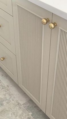 a bathroom with white cabinets and gold knobs