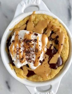 an ice cream dessert with chocolate and caramel drizzled on top in a white dish