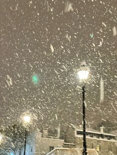 the snow is falling down on the street lights