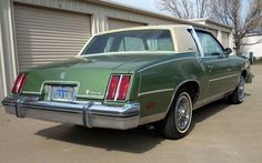 a green car parked in front of a garage