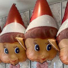 three large inflatable christmas elfs hanging from the side of a wall next to each other