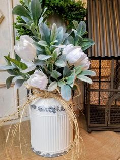 a white vase filled with flowers sitting on top of a table next to a wreath