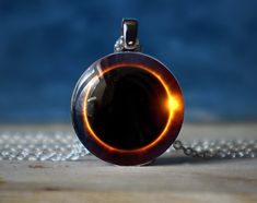 a glass pendant with a black hole in the center on a silver plated chain