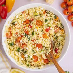 a white bowl filled with rice, tomatoes and cucumbers next to sliced lemons