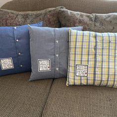 three pillows are sitting on the back of a couch with plaid and checkered designs