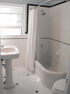 a white bath tub sitting next to a toilet and a sink in a small bathroom