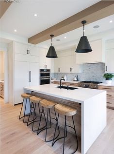 a kitchen with an island and stools in front of the counter top, surrounded by white cabinets