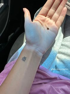 a person with a small tattoo on their arm holding up her hand in the air