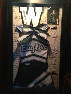 an eagle cheer uniform is displayed in a shadow box with the letter w on it