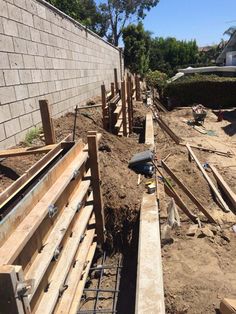 the back side of a house being built with wooden posts and wood slats on the ground