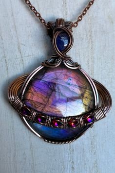 a wire wrapped pendant with multicolored glass in the center on a brown chain