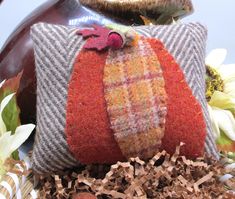 a decorative pumpkin pillow sitting on top of a pile of wood shavings